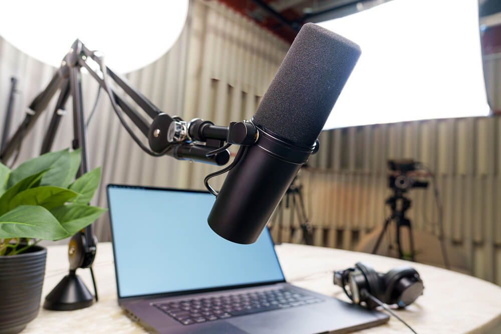 A microphone hanging above a laptop sat on a white table