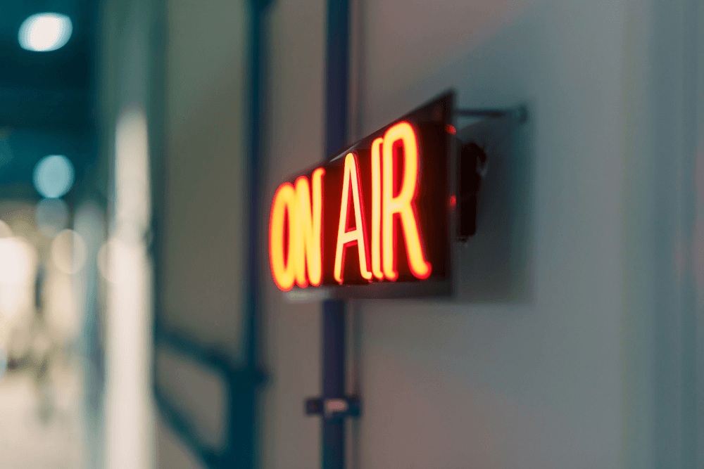 On Air sign in red neon on a grey wall